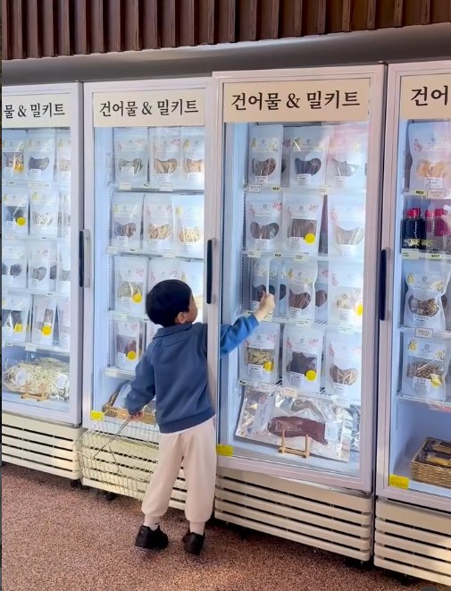 매장 냉장고에서 간식을 고르는 아이